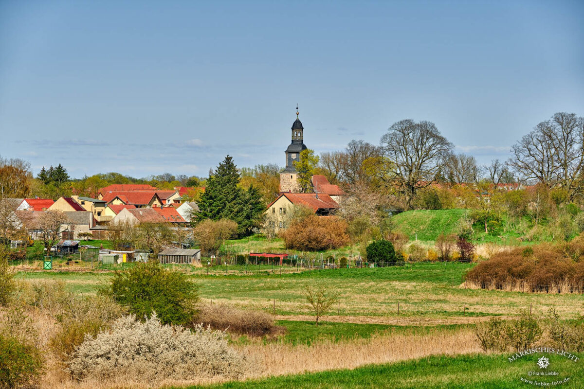 Eine Fernaufnahme von einem anderen Hügel zeigt rechts den Bosselberg, geradezu ein Teil des Dorfes Vehlefanz und seine Kirche.